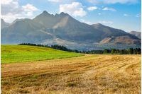 Tatra mountains in evening haze behind the forest and rural field