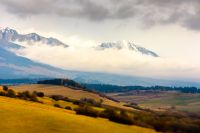 rural fields near Tatra Mountains in autumn season. beautiful view of countryside area of slovakia with forest on the hills. gorgeous mountain ridge with snow capped rocky peaks. miniature effect