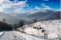 rural road in snowy mountainous area. beautiful winter scenery on a bright sunny day. mountains with snowy tops in a far distance