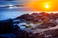 sea with rocky shore. day meet night. sun and moon over beautiful autumn equinox scenery and vacation concept on the rocky beach at twilight. scenic destination of seaside near old resort town