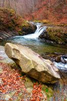 small waterfall on the turichka river in the forest near lumshory village of transcarpathia, ukraine. boulder on the shore. beautiful autumnal scenery. popular travel destination. wide angle