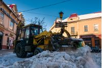 Uzhgorod, Ukraine - January 19, 2017: snow removal on streets of old town. people remove snow huge amount of snow with the help of  tractor with snowplow