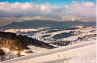 snowy slope in mountainous countryside. gorgeous weather with clouds over the mountain ridge. 