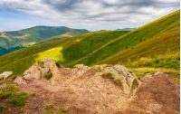 huge stones among the grass on top of the hillside meadow near the edge of a mountain cliff. vivid summer landscape.