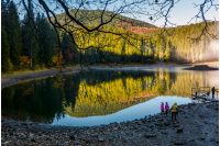National Park Synevyr, Ukraine - October 23, 2016: tourists on Synevyr lake in autumn. high altitude mountain lake among spruce forest. The most visited place in Carpathians on beautiful foggy morning