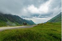 transfagarasan road in stormy weather. popular travel destination of romania. grassy meadow along on the edge of a hill. view in to the distant valley. overcast sky