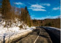 turnaround on the mountain road in winter. forested hills with snow on roadside under the clear blue sky