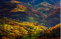 village in sunlit valley view from above. forest with golden foliage on hills. beautiful autumn evening