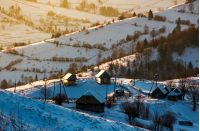 village on a snowy hillside at sunrise. beautiful countryside scenery in winter