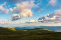 wonderful evening landscape. beautiful view from the grassy hill in to the distant valley and mountain ridge. fluffy clouds on the sky. peaceful idyllic scenery