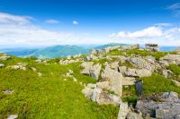 wonderful mountain landscape in summer. wide scenery with rock among grass on the hills and slopes under blue sky with fluffy clouds at high noon. scenic view of alpine environment