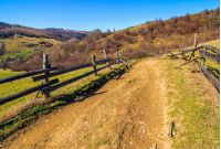 Spring time rural landscape. Wooden fence along the path through agricultural fields in Carpathian mountains