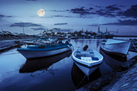 small fishing boats and few big one docked near embankment in port of Bulgarian town Sozopol at night in full moon light